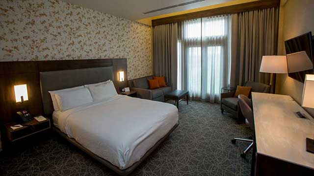 Bed and desk in front of window in room at Inn at Water's Edge