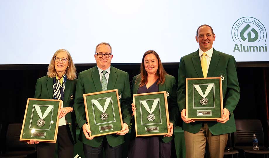Four distinguished alumni holding medallions