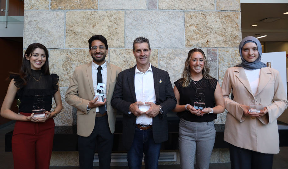 five award winners stand in a line holding their award