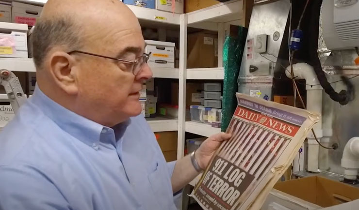 Mike Fagel reads a newspaper that showcases the twin towers being attacked