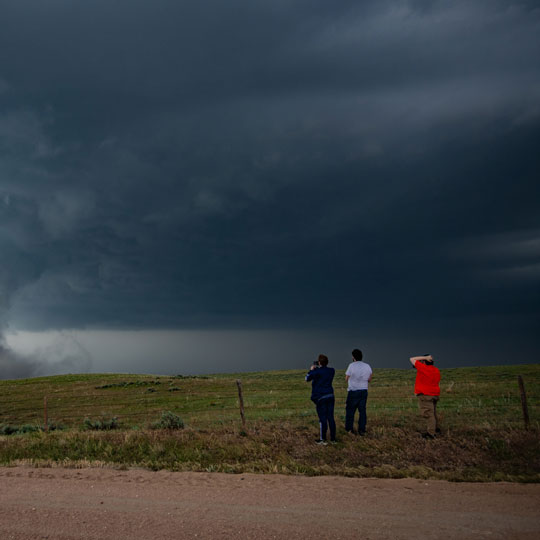 two students stand and look at a tornado forming in the air above